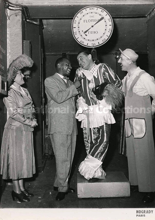 7 x 5 inch photography. Lionel Hampton with three unidentified persons in costumes, one of whom is on a weight scale that reads: The Florida Trio
