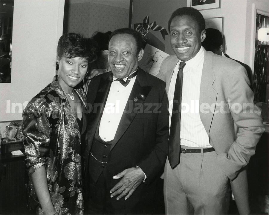 8 x 10 inch photograph. Lionel Hampton with unidentified woman and man at a reception