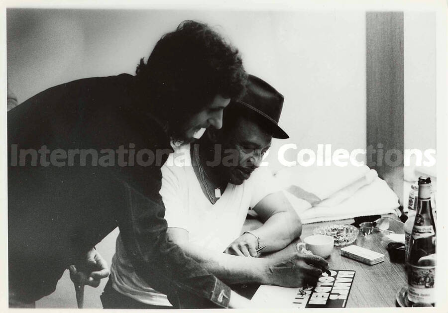 5 x 7 inch photograph. Lionel Hampton signs a copy of his record Hamps Golden Favorites