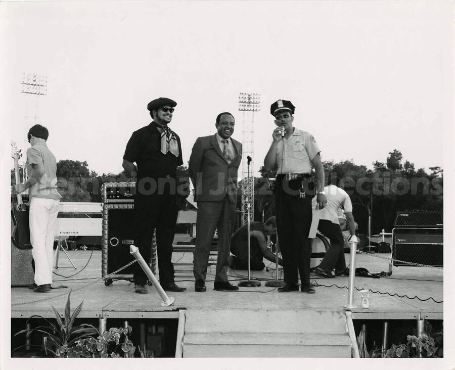 8 x 10 inch photograph. Lionel Hampton on an outdoor stage, with unidentified police officer and a man