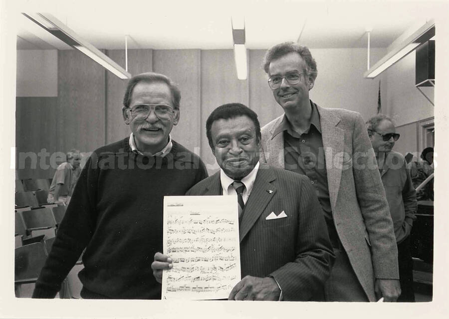 5 x 7 inch photograph. Lionel Hampton holds a score of a song with two unidentified men