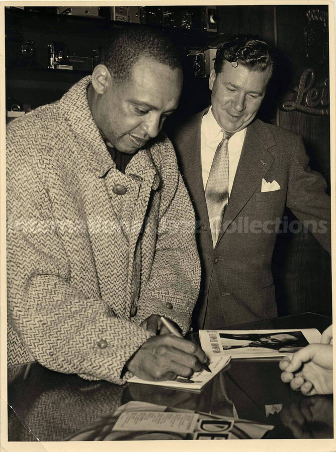 9 x 7 inch photograph. Lionel Hampton autographing for fans, in a store [abroad?]