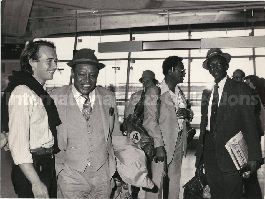 7 x 9 1/2 inch photograph. Lionel Hampton with unidentified men in an airport terminal