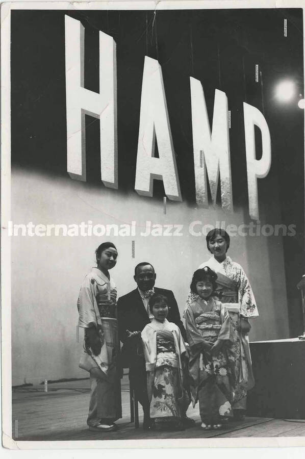 5 x 3 1/2 inch photograph. Lionel Hampton with girls dressed in Japanese costume [in Japan]