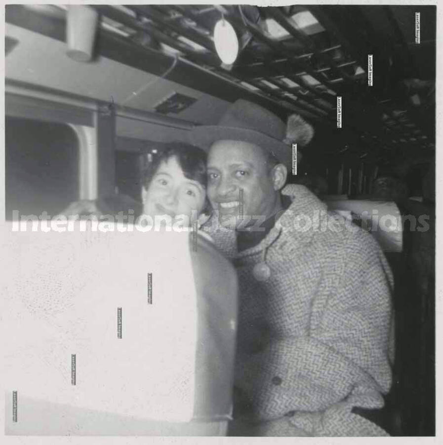 3 1/4 x 3 1/4 inch photograph. Lionel Hampton with unidentified woman [in a train?]. Handwritten on the back of the photograph: London, Ont[ario, Canada]