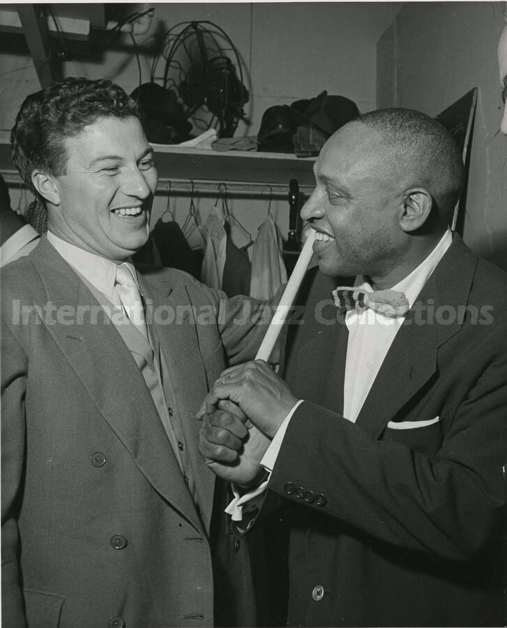 10 x 8 inch photograph. Lionel Hampton holding a drumstick in a pose of baseball player with bat alongside an unidentified man