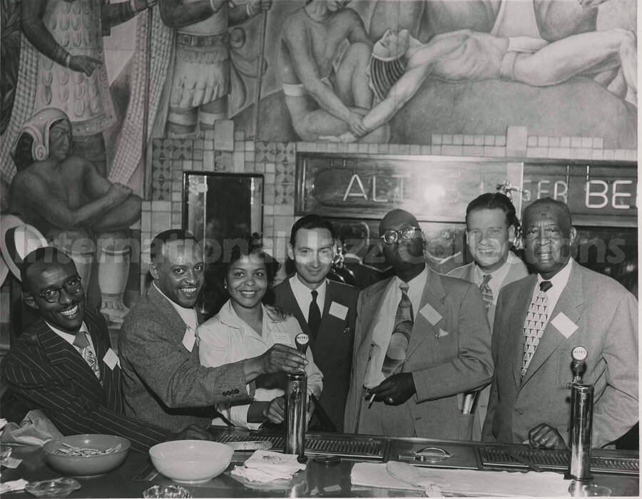 8 x 10 inch photograph. Lionel Hampton with unidentified persons at the tap room of the Altes Brewery, in Logan Heights, San Diego, CA. A sign on the wall reads: Altes Lager Beer