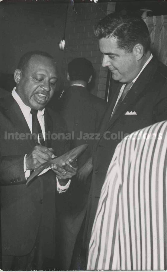5 1/2 x 3 1/2 inch photograph in the format of postcard. Lionel Hampton signing an autograph [in New Orleans, LA]