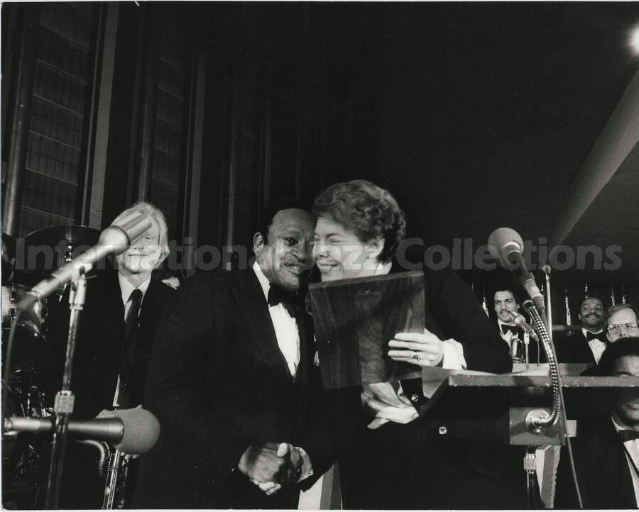 8 x 10 inch photograph. Lionel Hampton receiving from Jeane Jordan Kirkpatrick a plaque from the United States Mission that appointed him as Ambassador of Music to the United Nations