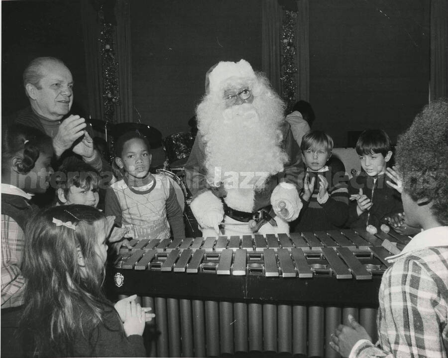 8 x 10 inch photograph. [Lionel Hampton?] dressed as Santa Claus, plays the vibraphone surrounded by children