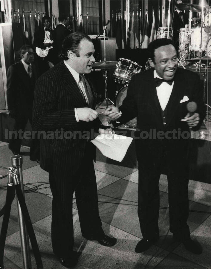 10 x 8 inch photograph. Lionel Hampton with a man on the occasion of his receiving a plaque from the United States Mission that appointed him as Ambassador of Music to the United Nations. Handwritten on the back of the photograph: M[ario] Alberto Voss Rubio