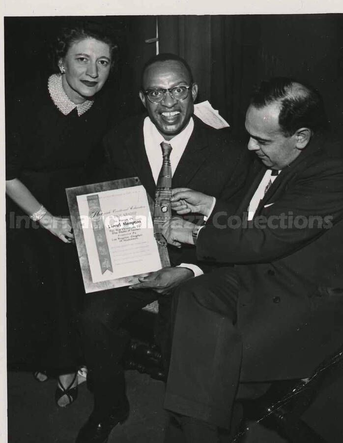 5 x 3 1/2 inch photograph. Lionel Hampton holding a plaque poses with members of the Los Angeles Chapter of Hadassah, on the occasion of his being awarded the certificate of the Hadassah Vocational Education Scholarship for his devotion to the State of Israel. Los Angeles, CA
