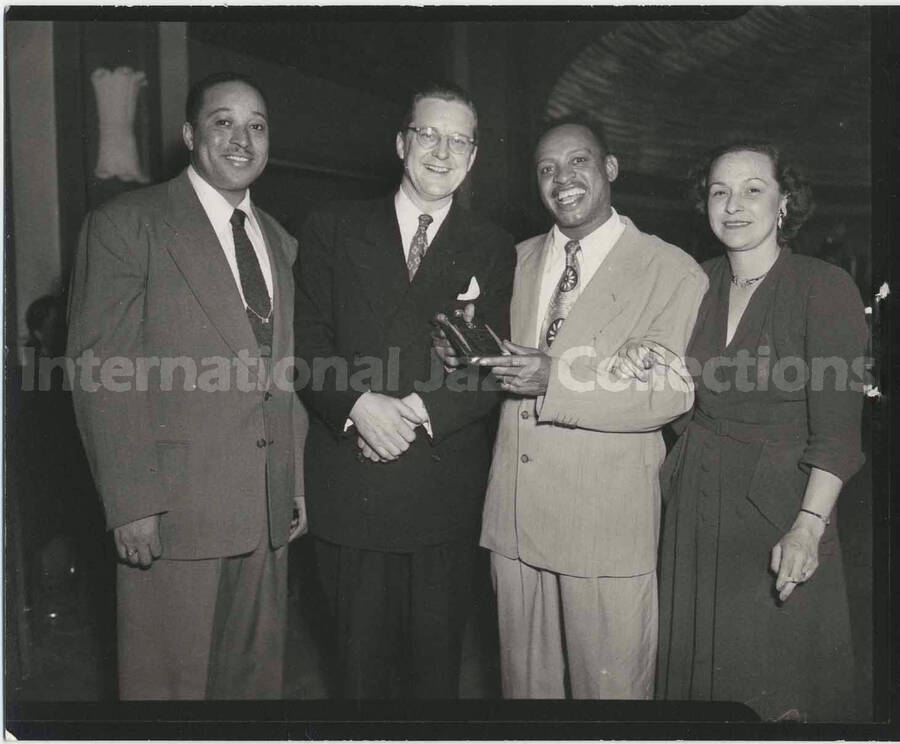 4 x 5 inch photograph. Lionel Hampton holding a small [plaque?] with two unidentified men and a woman