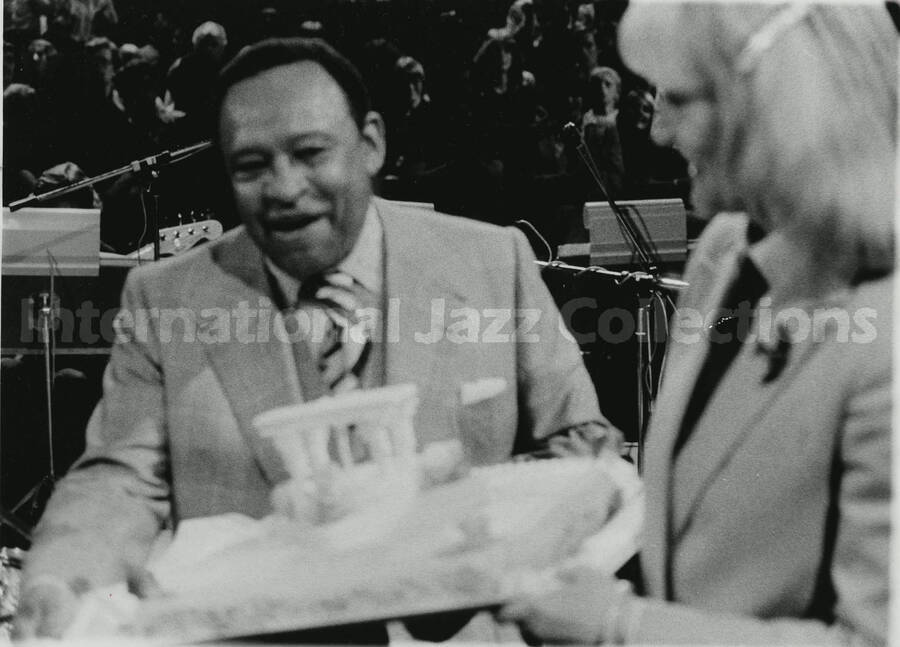 8 x 10 inch photograph. Lionel Hampton presented with a [birthday?] cake by an unidentified woman