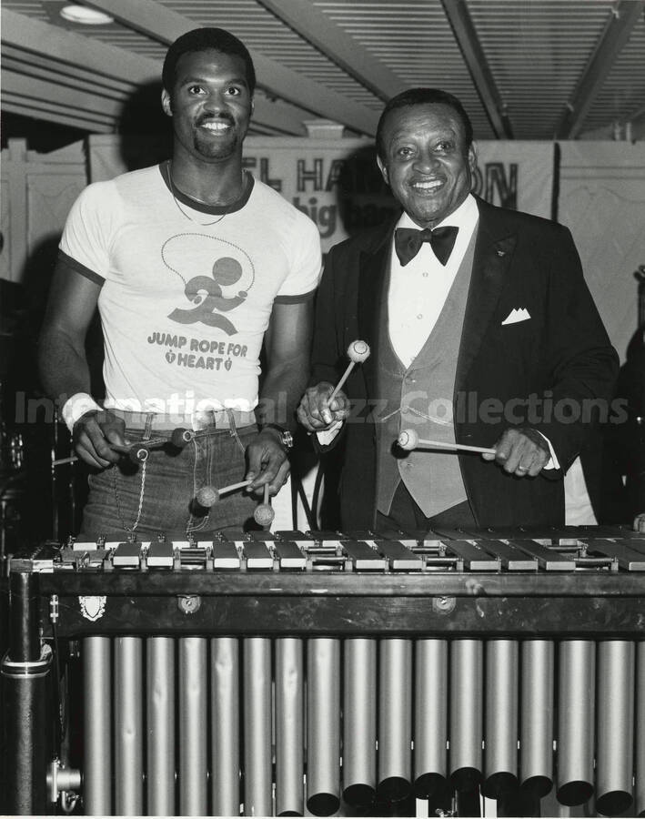10 x 8 inch photograph. Lionel Hampton stands behind the vibraphone with unidentified man, both are holding mallets. The man's shirt reads: Jump Rope for Heart. [Disneyland?]