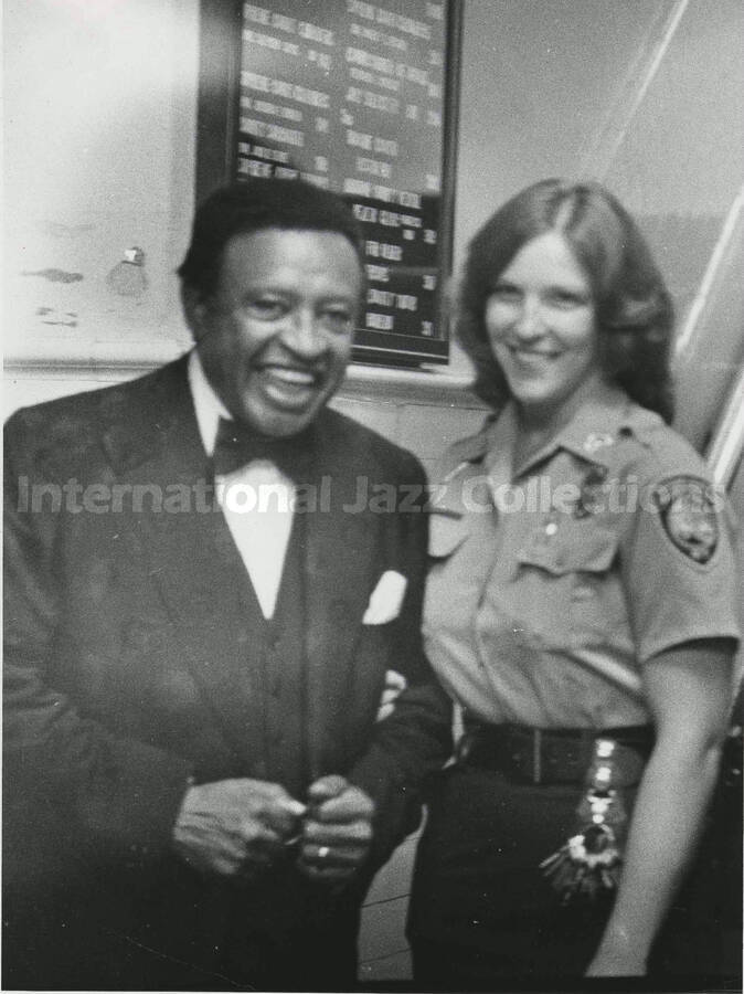 8 1/2 x 6 1/2 inch photograph. Lionel Hampton stands with unidentified police personnel