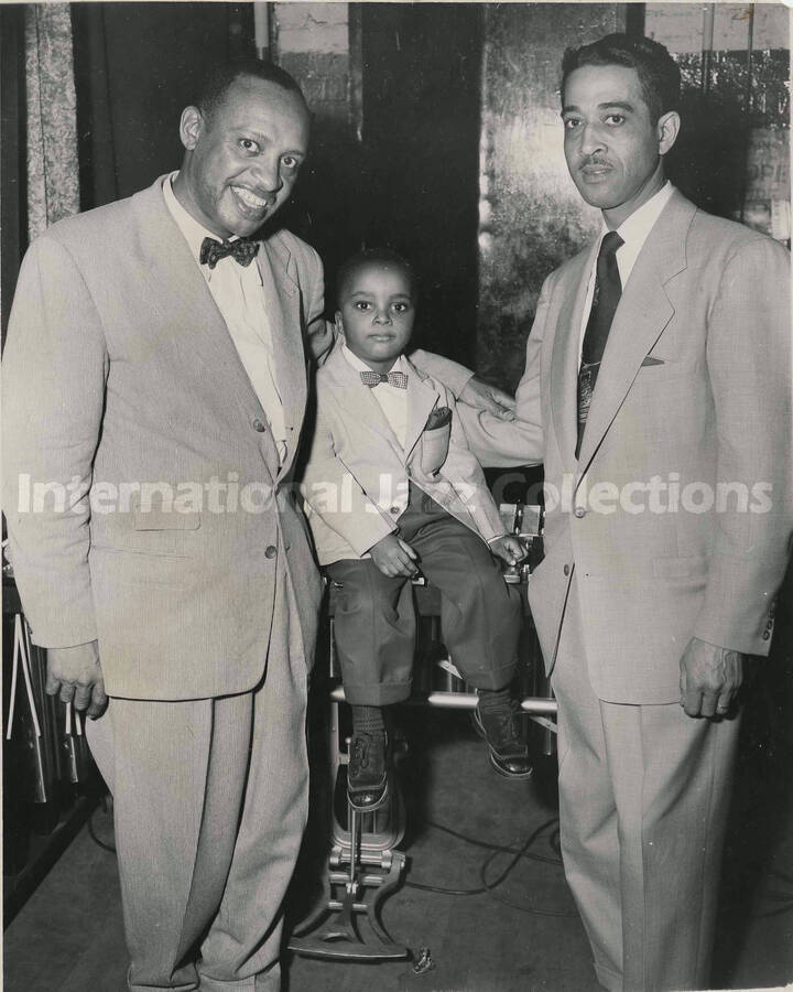 10 x 8 inch photograph. Lionel Hampton with unidentified man and a boy. The boy is sitting on the vibraphone