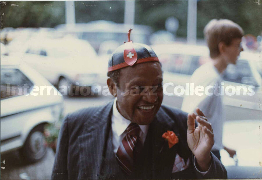 5 x 7 1/4 inch photograph. Lionel Hampton wearing a black and red hat with a white cross