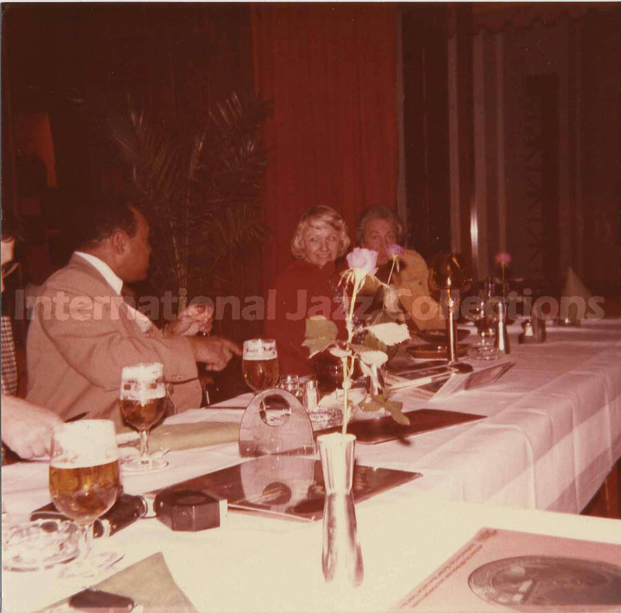 5 x 5 inch photograph. Lionel Hampton with Bill Titone and an unidentified woman at a dinner table