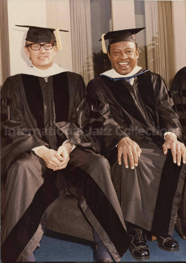 7 x 5 inch photograph. Lionel Hampton in graduation garb with unidentified man [on the occasion of his receiving a honorary degree from Pepperdine University?]