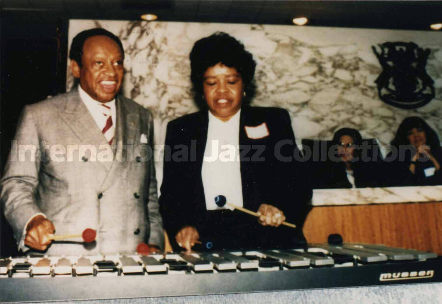 3 1/2 x 5 inch photograph. Lionel Hampton playing the vibraphone with unidentified woman, on the occasion of his receiving a plaque, in Detroit, Michigan
