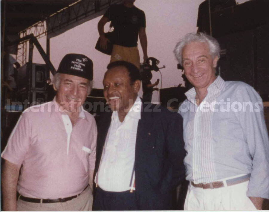 3 1/2 x 4 1/2 inch photograph. Lionel Hampton back stage with George Wein and Bill Titone. Wein is wearing a hat of the 1985 Newport Folk Festival Folk Festival
