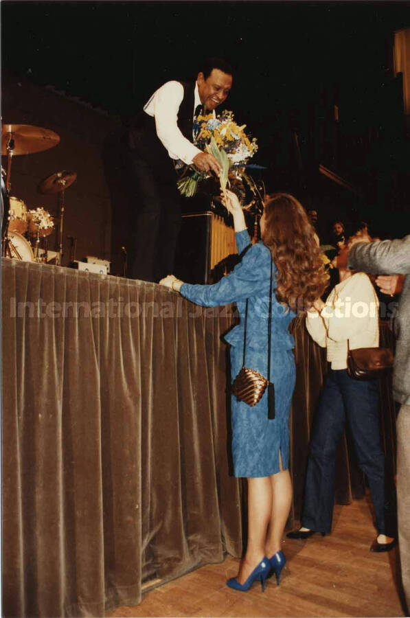 5 x 3 1/2 inch photograph. Lionel Hampton receives flowers from an unidentified woman