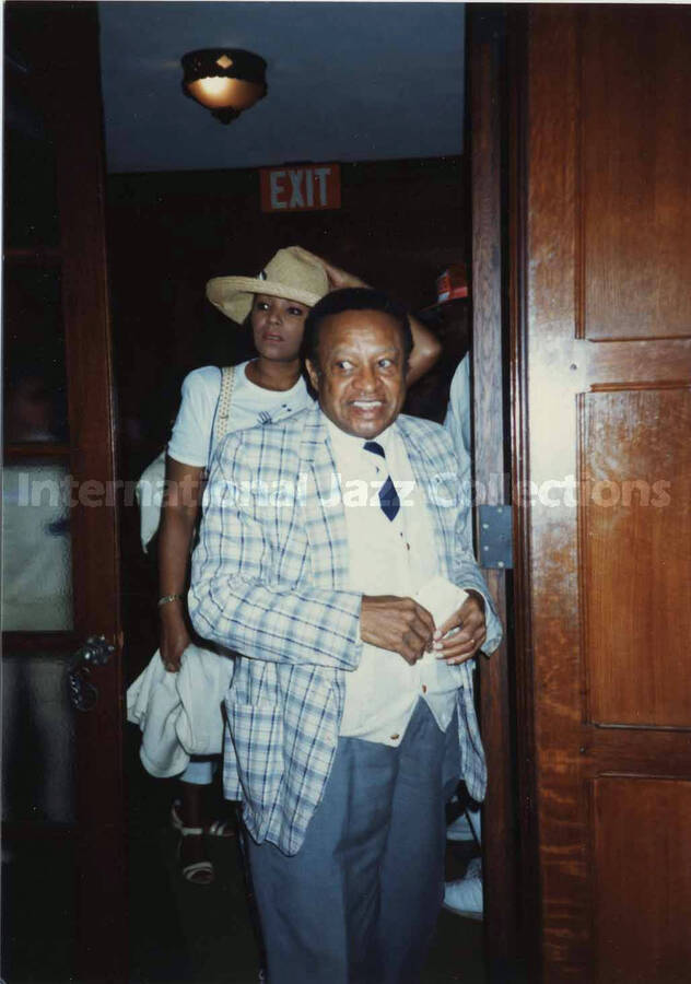 5 x 3 1/2 inch photograph. Lionel Hampton walking through a door, on the occasion of the Jazzy [Summer jazz festival in Yonkers, NY?]
