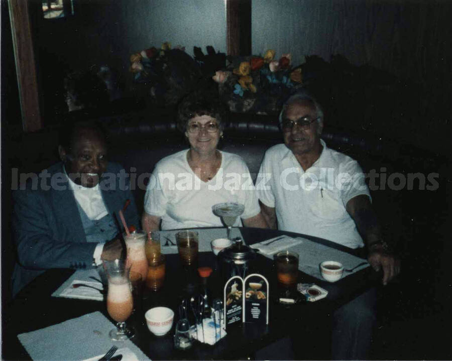 3 1/2 x 4 1/2 inch photograph. Lionel Hampton sits at a dinner table with unidentified couple