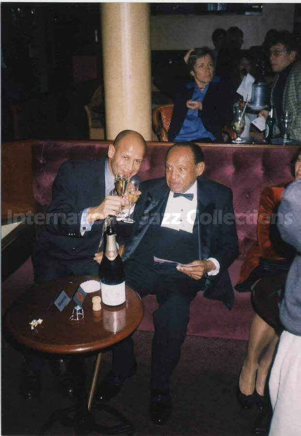 5 x 3 1/2 inch photograph. Lionel Hampton shares a toast with unidentified man