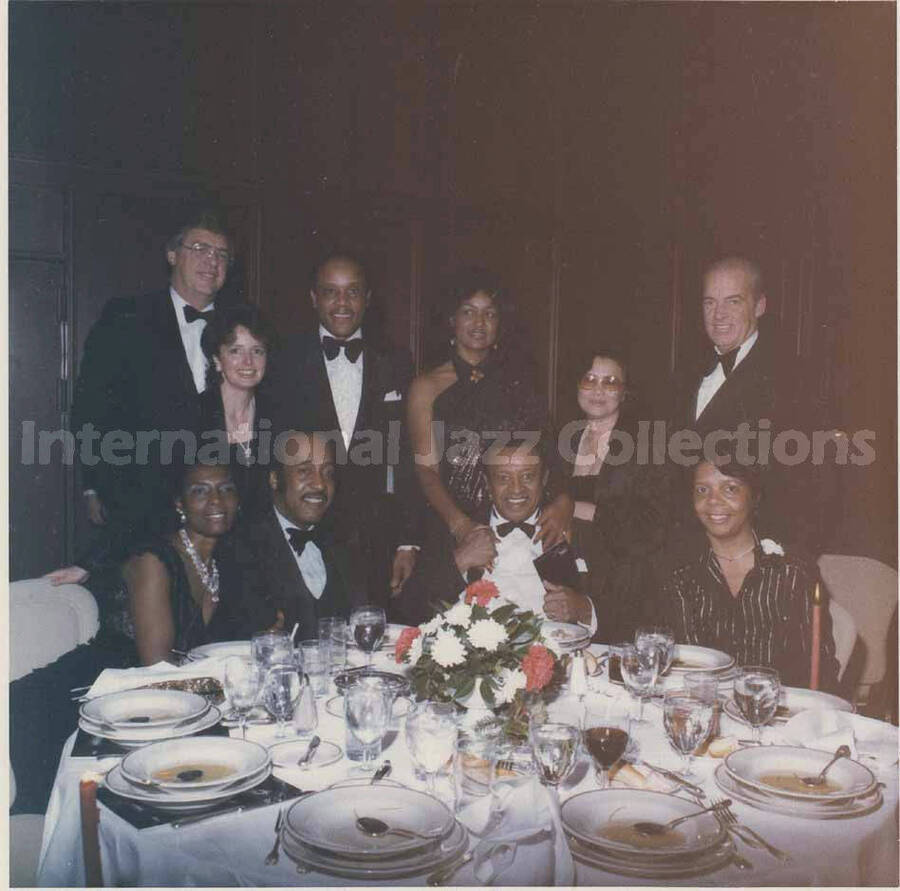 3 1/2 x 3 1/2 inch photograph. Lionel Hampton at a dinner table with unidentified persons, in a ceremony at the Garden City Hotel