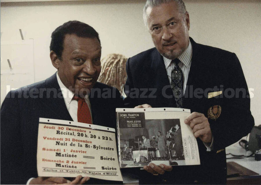 5 x 7 inch photograph. Lionel Hampton with unidentified man holding an old program from a concert at the Palais d'Hiver