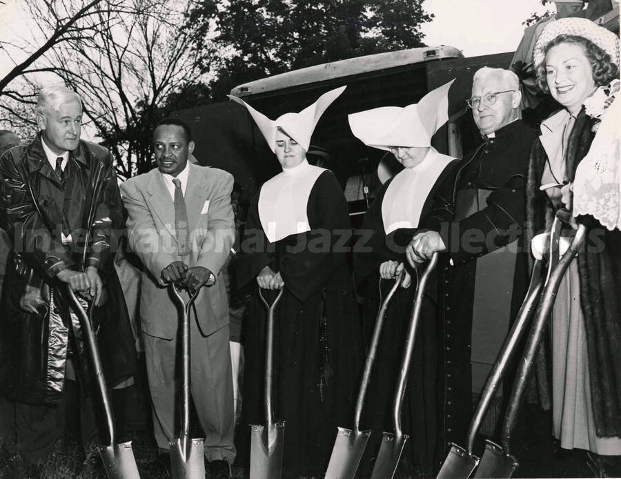 8 x 10 inch photograph. Lionel Hampton with unidentified persons, including two catholic nuns, each of them leaning on their shovels