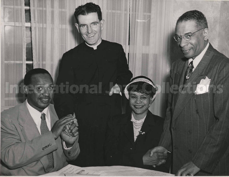 8 x 10 inch photograph. Lionel Hampton with unidentified persons, including a priest
