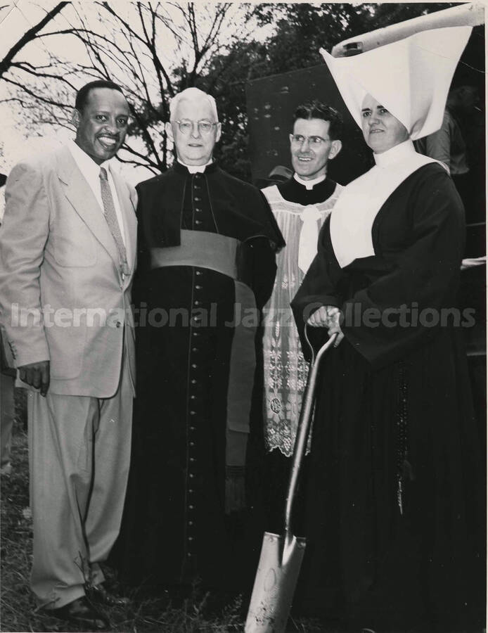 10 x 8 inch photograph. Lionel Hampton with unidentified religious persons, including a catholic nun leaning on her shovel