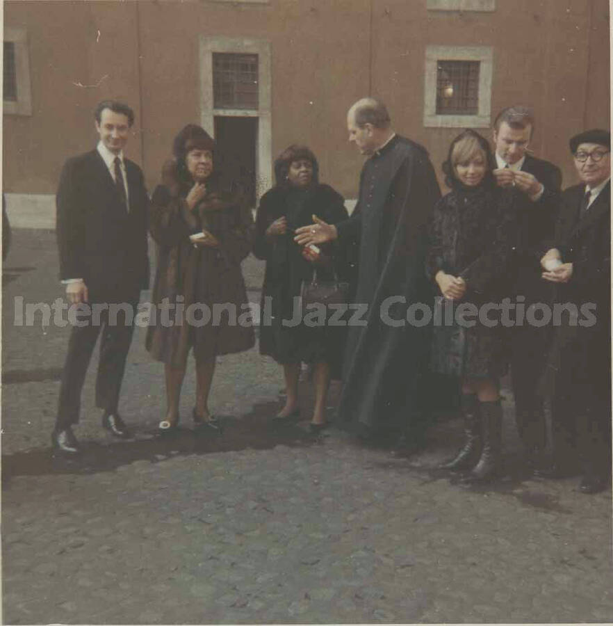 3 1/2 x 3 1/2 inch photograph. Bill Titone and Gladys Hampton with unidentified persons, including a representative of the catholic church, [in Rome, Italy?]
