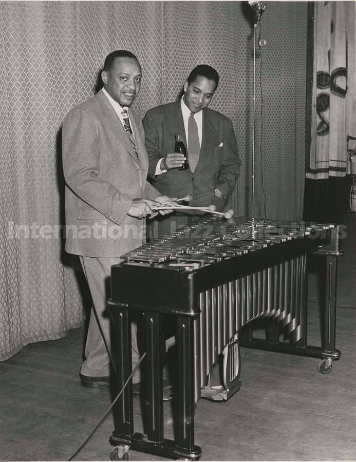 10 x 8 inch photograph. Lionel Hampton poses at the vibraphone with Moss Kendrix holding a bottle of Coca-Cola