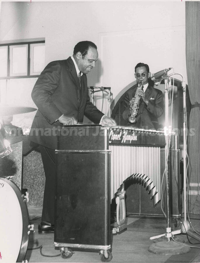 10 x 8 inch photograph. Lionel Hampton performing on the vibraphone accompanied by a clarinetist. Handwritten on the back of the photograph: King of Thailand jams with Hamp