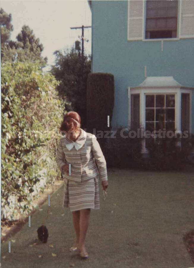 3 1/2 x 3 1/2 inch photograph. Gladys Hampton walking her dog in the yard of the Hampton home