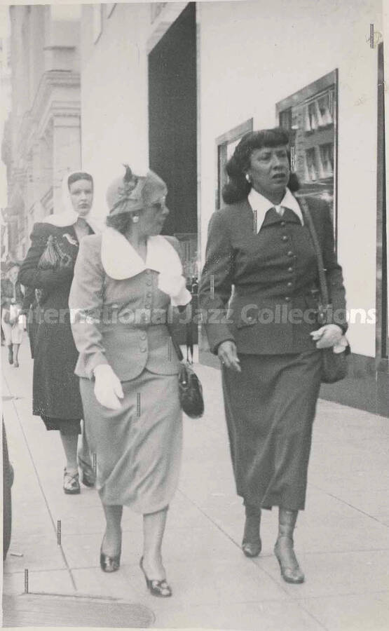 5 1/2 x 3 1/2 inch photograph. Gladys Hampton walking down a street with unidentified woman