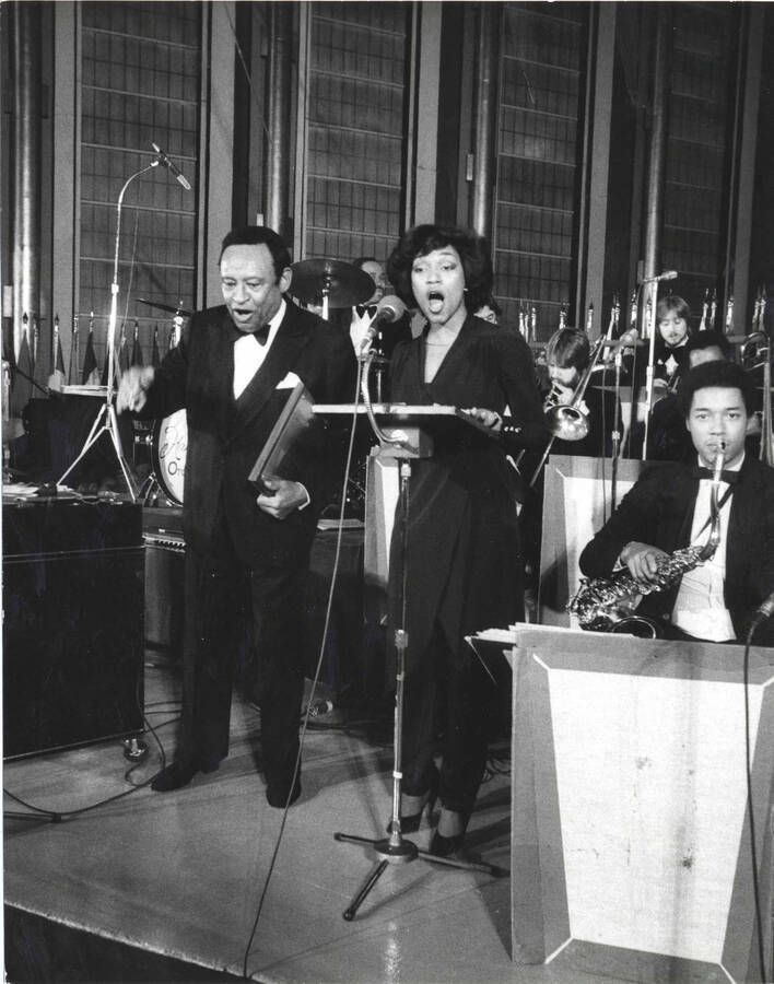 10 x 8 inch photograph. Lionel Hampton with unidentified woman and orchestra, on the occasion of his receiving a plaque from the United States Mission that appointed him as Ambassador of Music to the United Nations