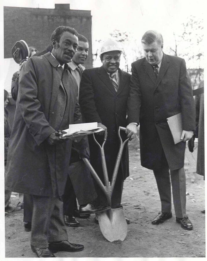 10 x 8 inch photograph. Lionel Hampon with unidentified men holding a shovel with three handles at the ground breaking ceremony of the Lionel Hampton Houses