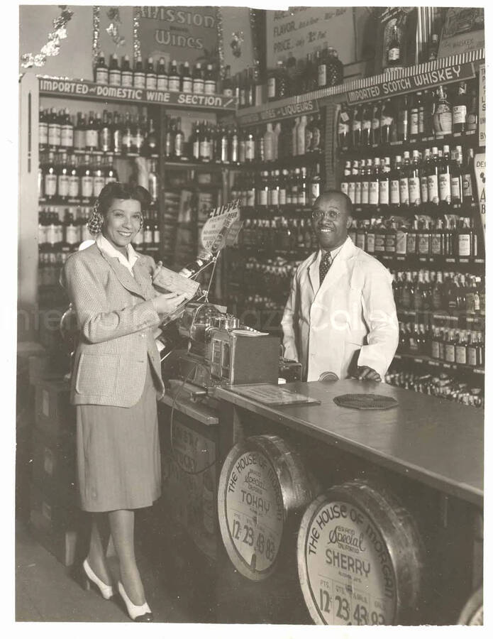 9 x 8 inch photograph. Gladys Hampton stands holding a check in the House of Morgan liquor store