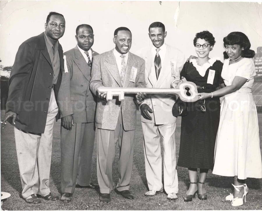 7 1/2 x 9 1/2 inch photograph. Lionel and Gladys Hampton with unidentified persons. They are holding a big ceremonial key on the occasion of an event related to jazz