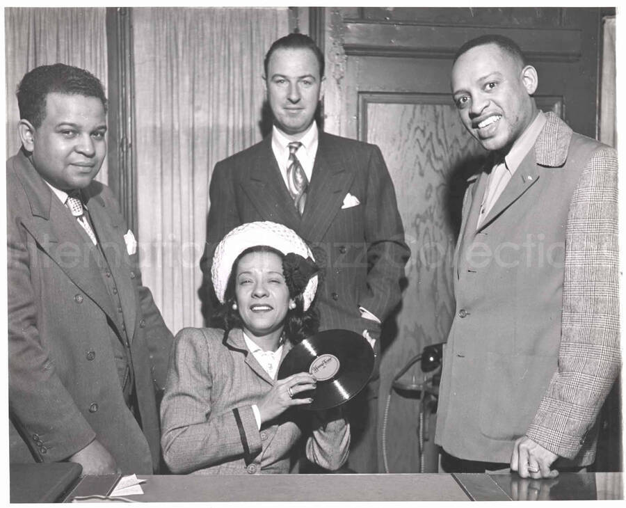 8 x 10 inch photograph. Lionel and Gladys Hampton with unidentified men. Gladys is holding the record Hamp Tone