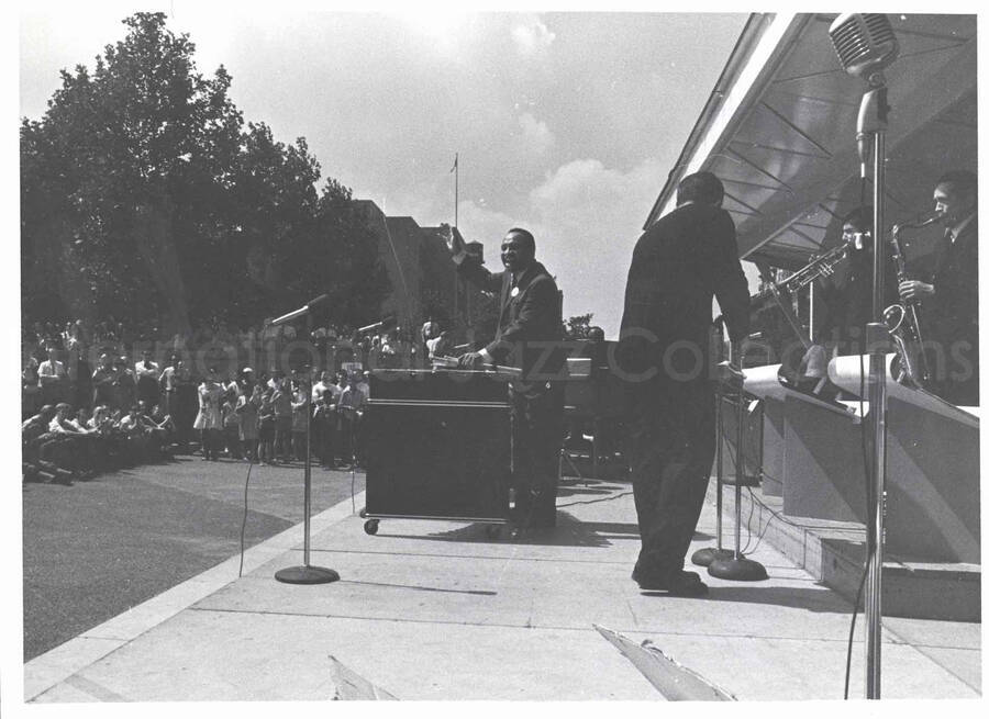 8 x 10 inch photograph. Lionel Hampton at an outdoor concert. Posters on the background of the stage reads: Fun Day