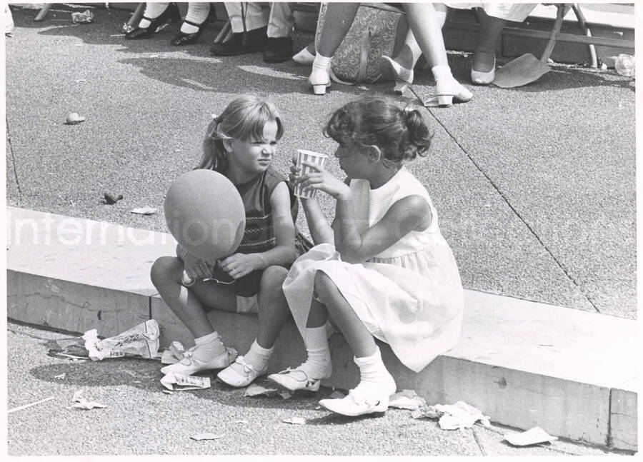 8 x 10 inch photograph. Two girls sipping drinks during Lionel Hampton's outdoor concert