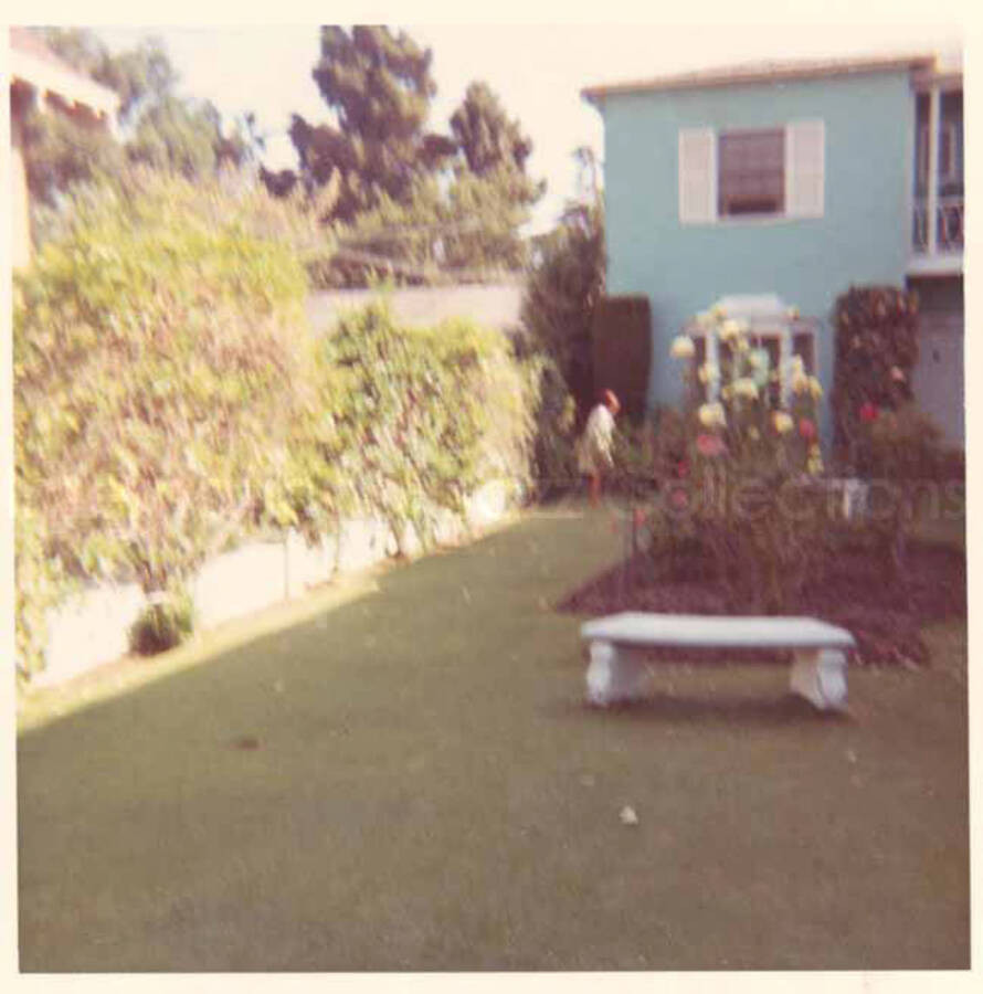 Gladys Hampton walking her dog in the yard of the Hampton home. 3 1/2 x 3 1/2 inch photograph.