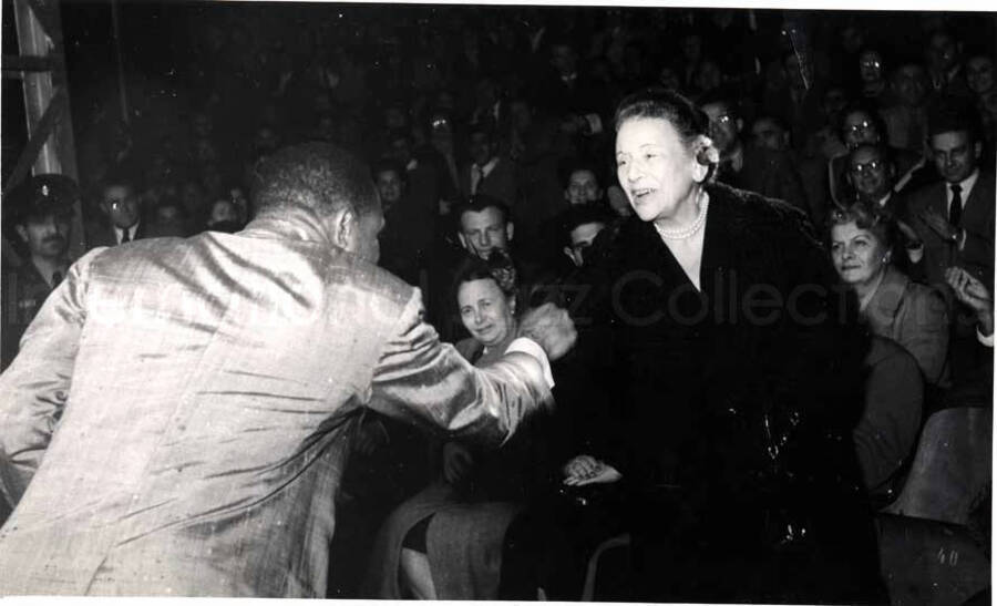 5 x 8 inch photograph. Lionel Hampton performing with band in Israel. Lionel Hampton shakes hands with unidentified woman in the audience