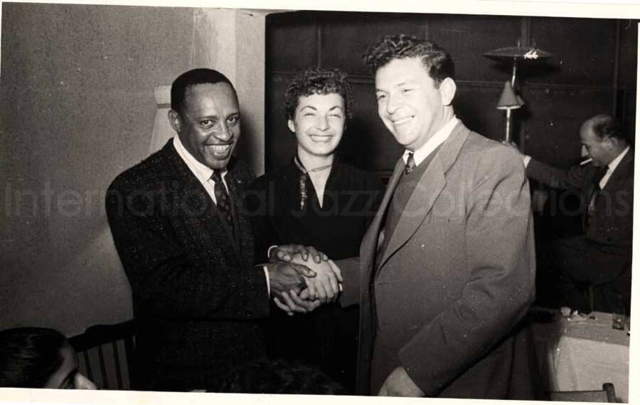 5 x 8 inch photograph. Lionel Hampton with unidentified woman and man in a restaurant in Israel